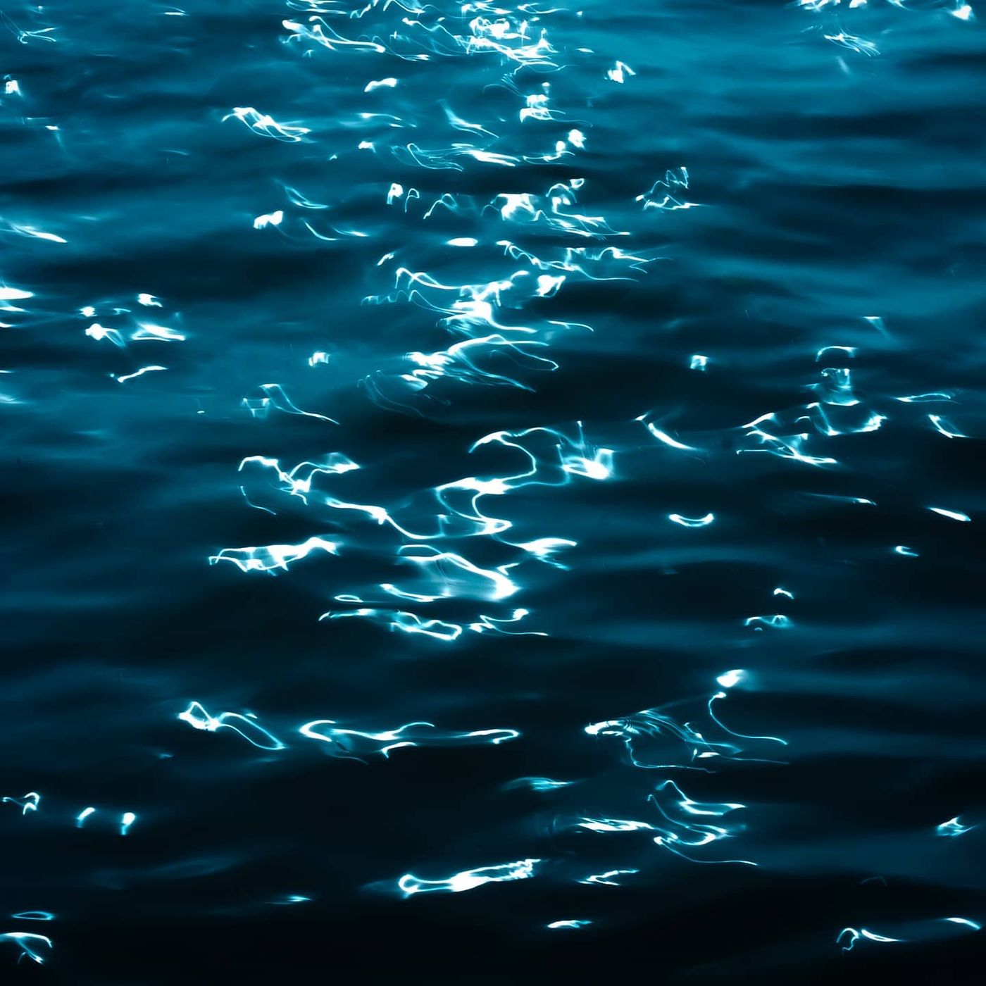 Streaks of light dancing on dark teal water